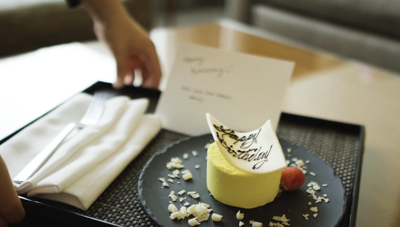 A room service tray with a birthday dessert and a handwritten note, set down for a Four Seasons guest.