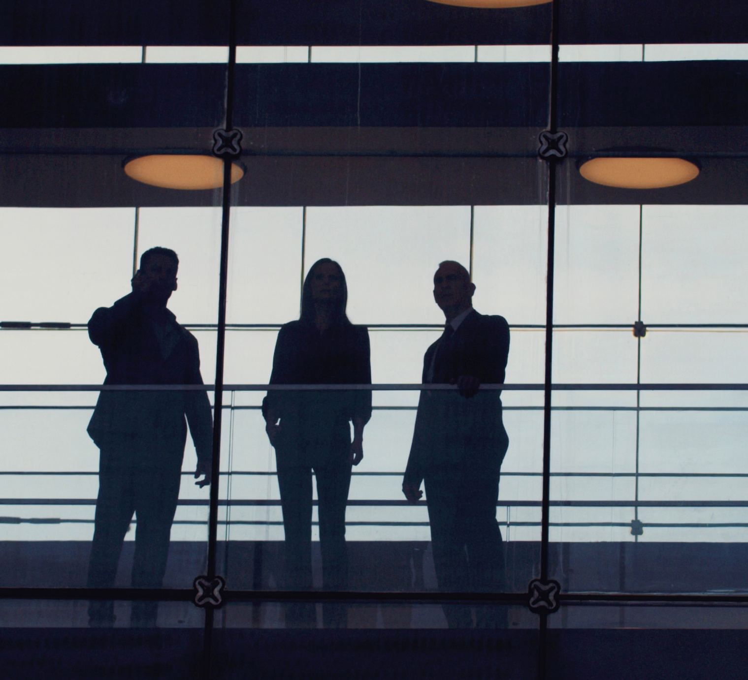 Three silhouetted leaders standing at a railing
